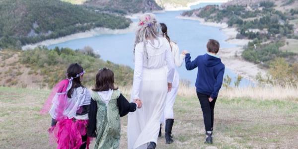 Donne e bambini in costume si tengono per mano davanti a un lago