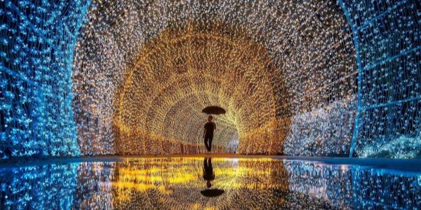 Un tunnel di luci colorate con una persona sotto la pioggia